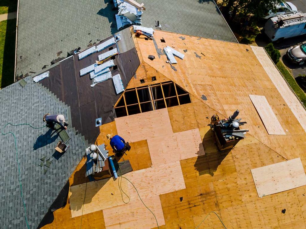 A close-up view of damaged asphalt roof shingles showing curling edges and surface cracks.